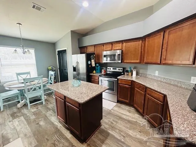 a kitchen with stainless steel appliances granite countertop a stove a sink dishwasher a microwave oven and a dining table with wooden floor