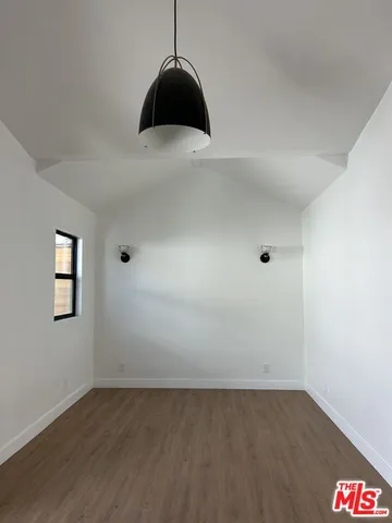 a view of an empty room with wooden floor and a hallway