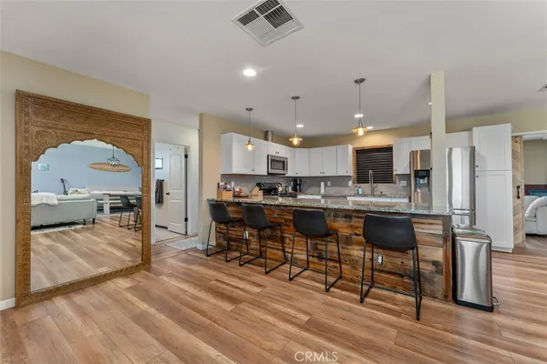 a kitchen with stainless steel appliances kitchen island granite countertop a table chairs sink and cabinets