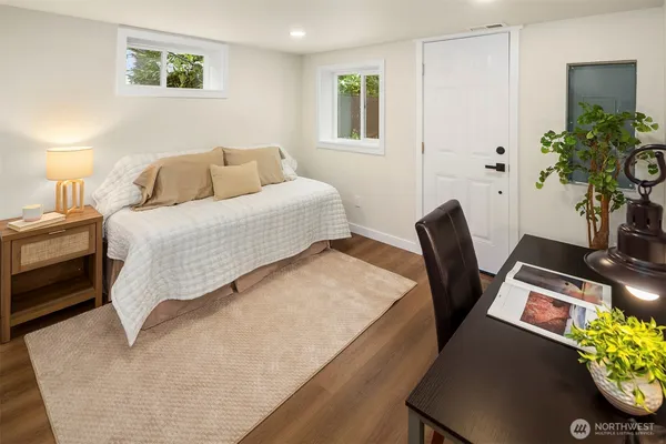 a bedroom with a bed table flowerpot and a window