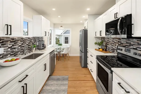 a kitchen with stainless steel appliances a stove top oven a sink a refrigerator and white cabinets