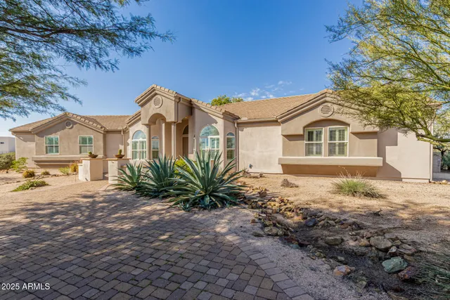 a front view of a house with a dirt yard and a large tree