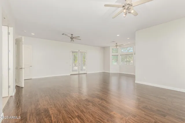 an empty room with wooden floor and windows