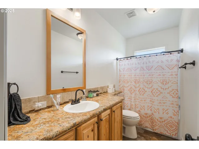 a bathroom with a granite countertop sink a toilet a mirror and shower curtain