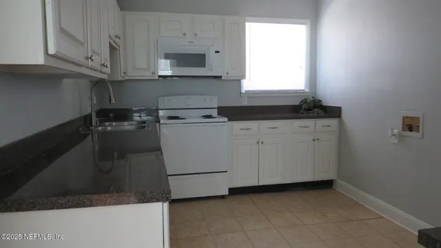 a kitchen with granite countertop white cabinets and white appliances