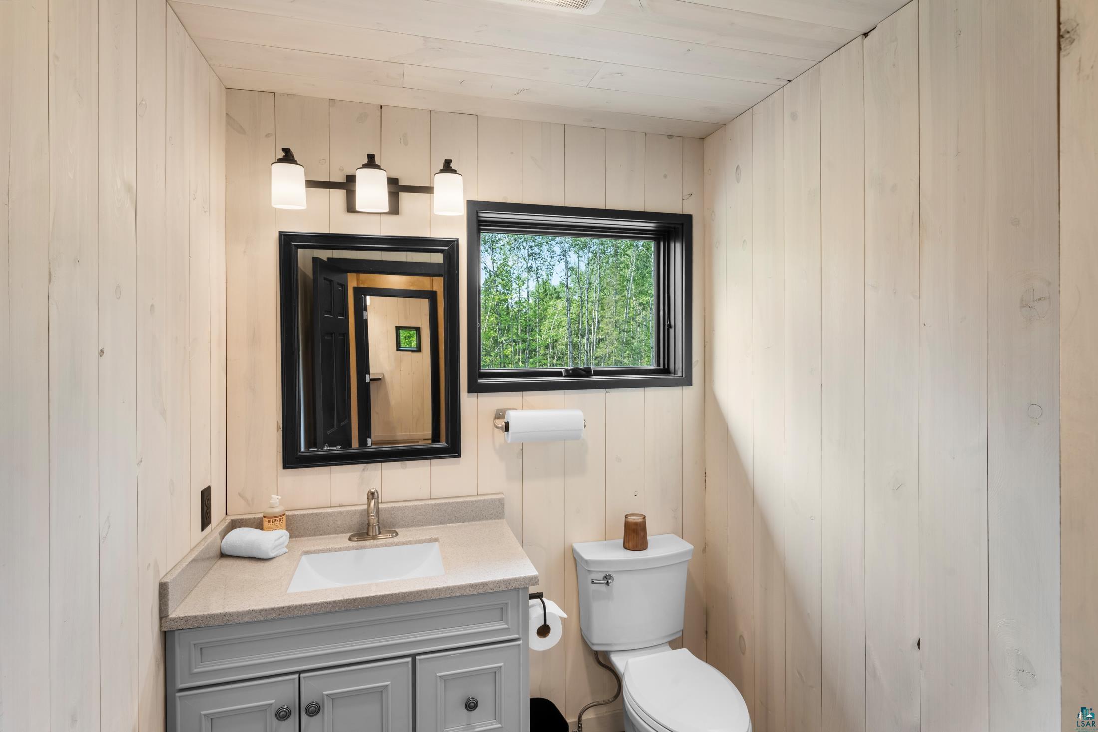3778 East County Road Barnum, MN 55707 - Photo 40 of 52 Vertical wood paneling, wood-finish ceiling, vanity with undermount sink, three-light fixture, and rectangular window