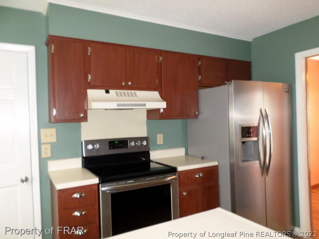 6712 Vaughn Road Fayetteville, NC 28304 - Photo 9 of 19 a kitchen with a refrigerator and a stove top oven