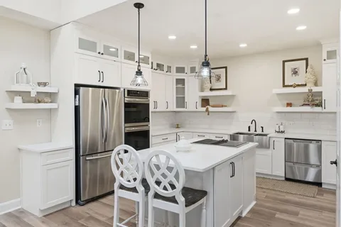 a kitchen that has a table chairs stainless steel appliances and cabinets