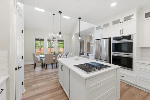 a kitchen that has a kitchen island stainless steel appliances a refrigerator table and chairs