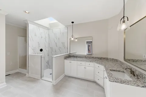 a spacious bathroom with a granite countertop sink a mirror and shower