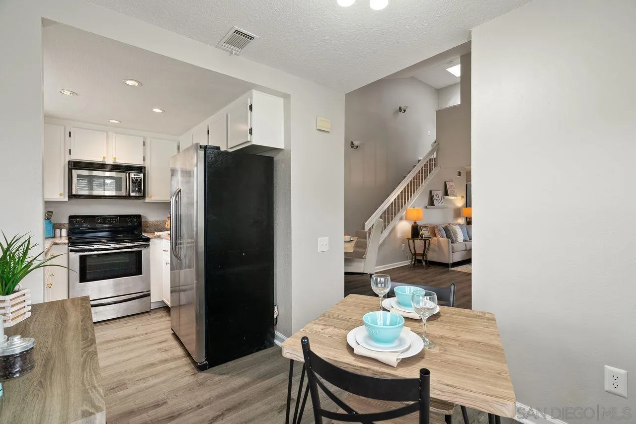4765 Adler Way Oceanside, CA 92057 - Photo 14 of 33 a kitchen with stainless steel appliances a refrigerator a stove a microwave and a dining table with wooden floor