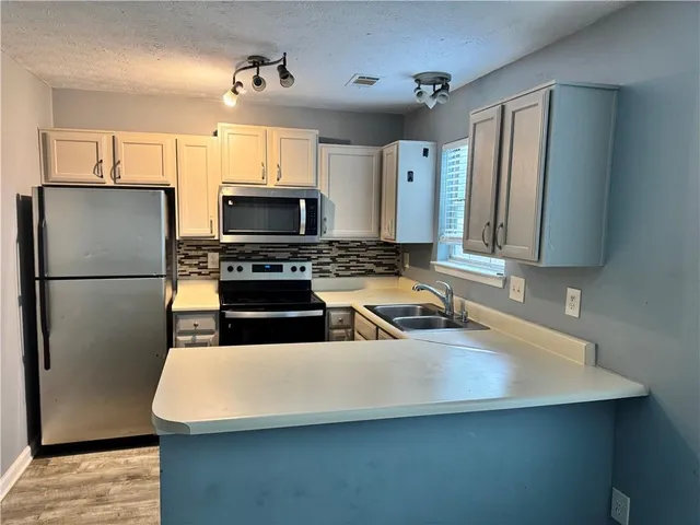 a kitchen with stainless steel appliances a refrigerator a stove a sink a center island and cabinets