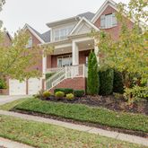 a view of a white house next to a yard with a tree