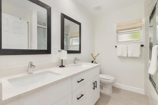 a bathroom with double vanity sink a mirror and a toilet