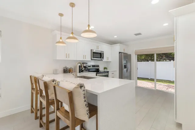 a kitchen with stainless steel appliances kitchen island granite countertop a refrigerator a stove a microwave oven a sink with a dining table and chairs