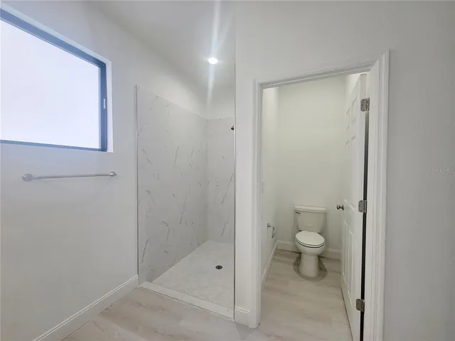 a bathroom with a granite countertop sink a toilet and a shower