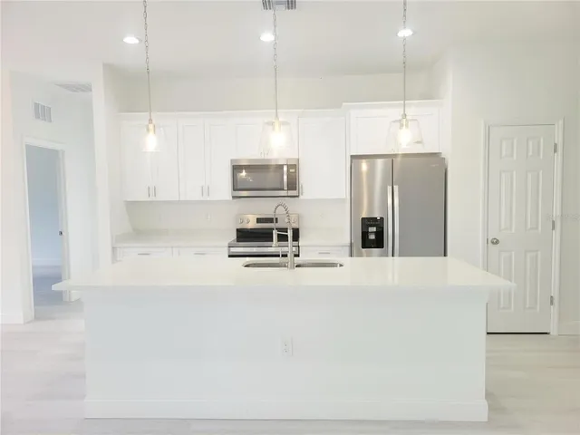 a large kitchen with stainless steel appliances a refrigerator and a stove