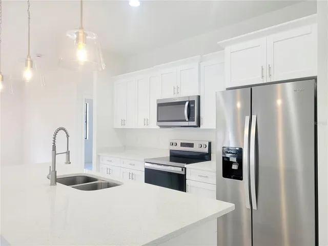 a kitchen with stainless steel appliances a refrigerator sink and white cabinets