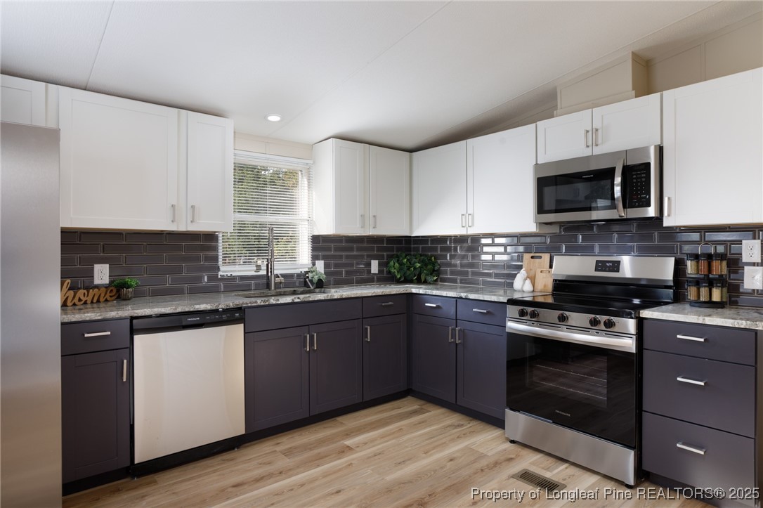 212 Heflin Road Aberdeen, NC 28315 - Photo 6 of 23 a kitchen with stainless steel appliances granite countertop a stove a sink and a microwave