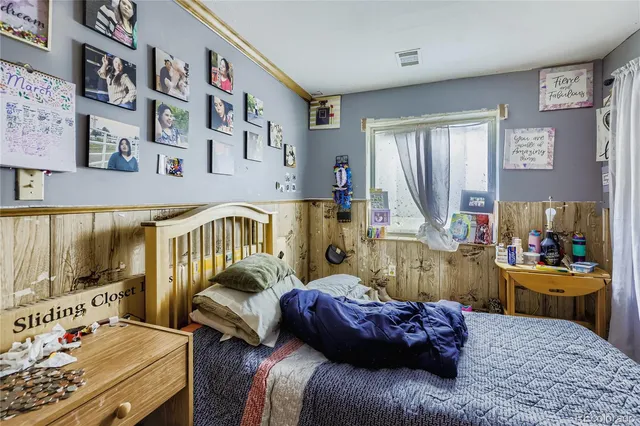 a bedroom with a bed painting on wall and a desk