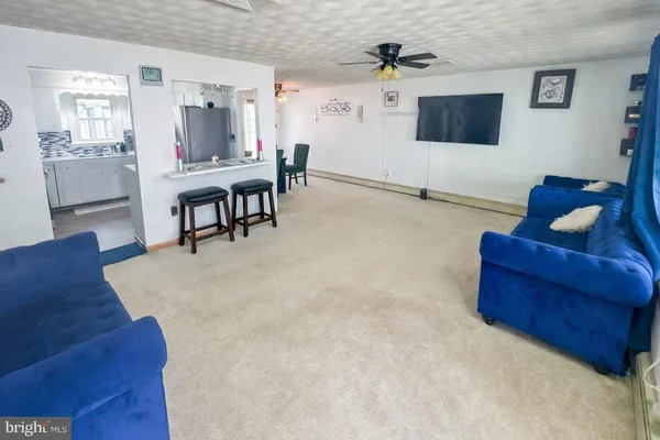 a living room with furniture a flat screen tv and kitchen view