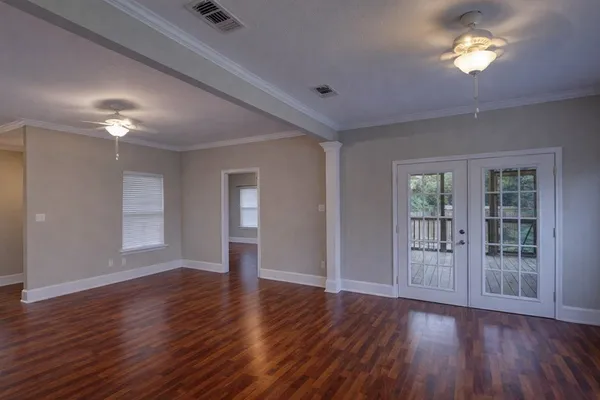 a view of an empty room with wooden floor and a window