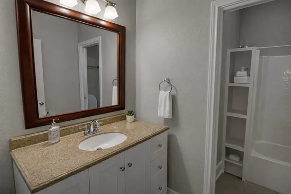 a bathroom with a granite countertop sink and a mirror