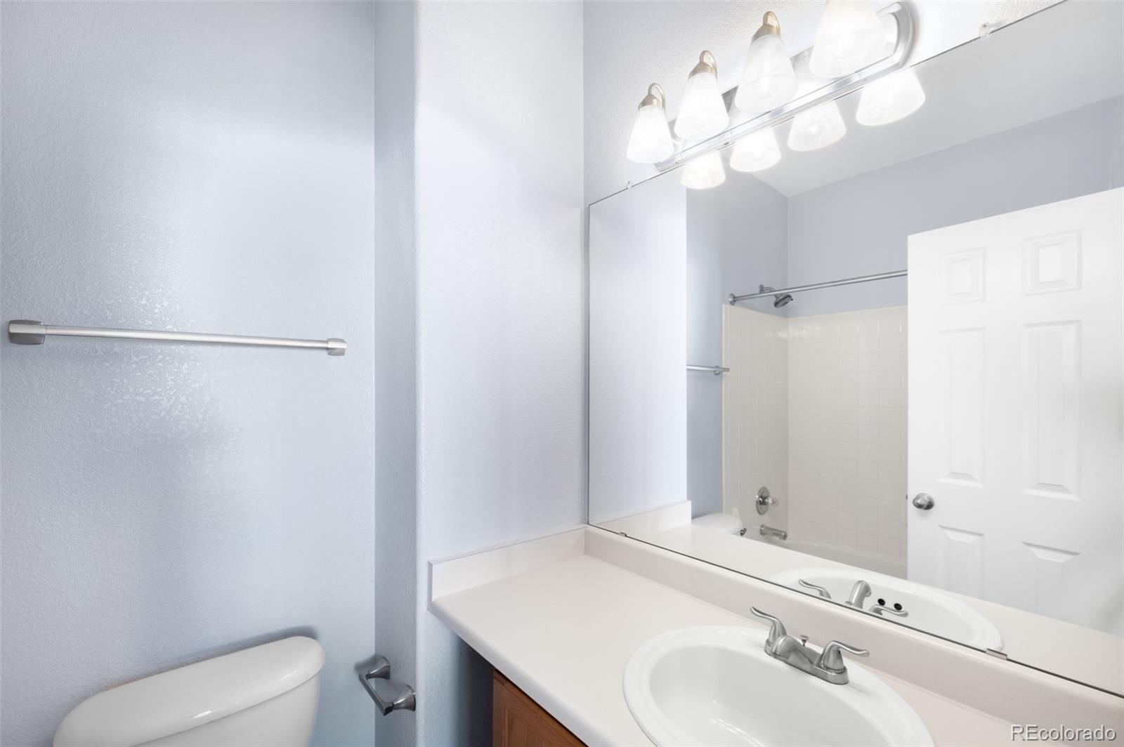 8199 Welby Road, Unit 3102 Denver, CO 80229 - Photo 13 of 18 a bathroom with a sink vanity mirror and toilet
