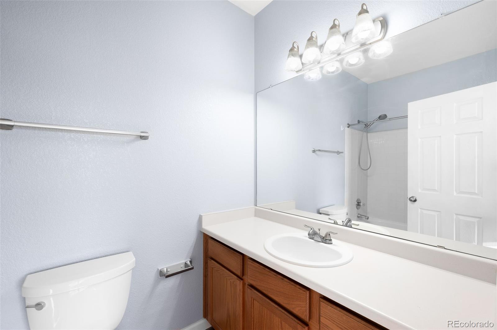 8199 Welby Road, Unit 3102 Denver, CO 80229 - Photo 16 of 18 a bathroom with a sink vanity mirror and toilet