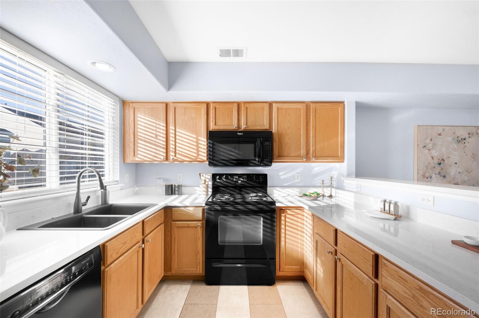 8199 Welby Road, Unit 3102 Denver, CO 80229 - Photo 7 of 18 a kitchen with a sink stove top oven and cabinets