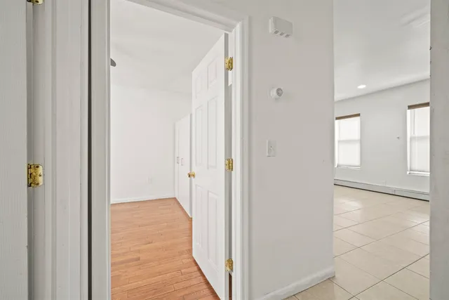 a view of a hallway with wooden floor and a bathroom