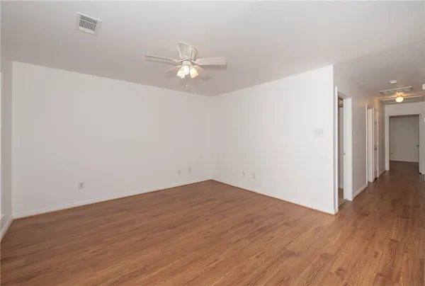 an empty room with wooden floor and a ceiling fan