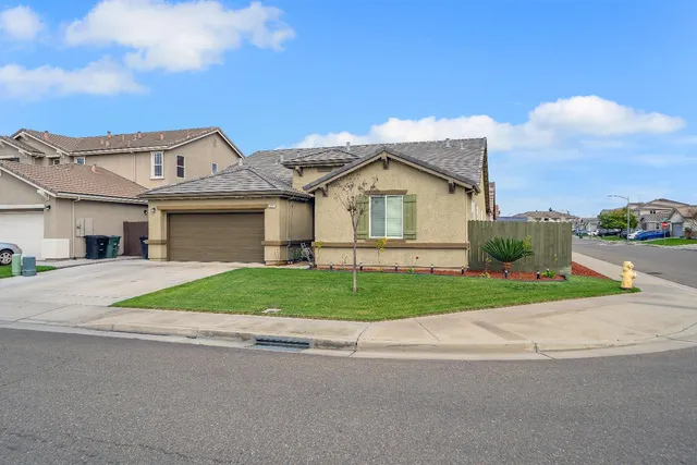 a view of a house with a yard and large tree
