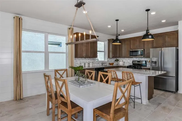 a kitchen with stainless steel appliances granite countertop a stove a refrigerator a kitchen island a sink and a refrigerator