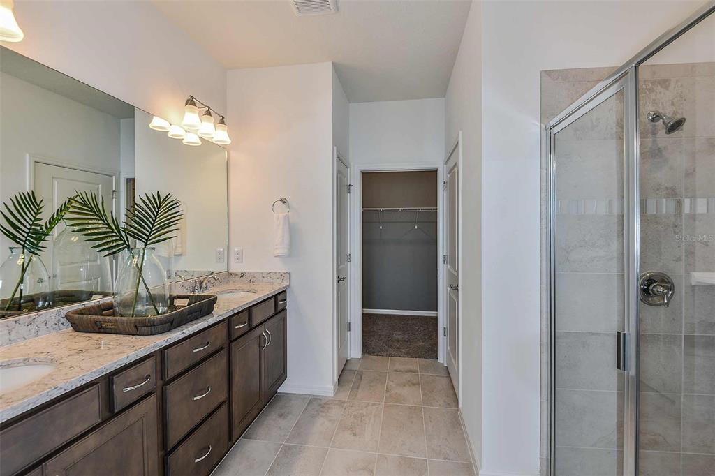 2354 Dew Drop Loop St. Cloud, FL 34771 - Photo 17 of 31 a bathroom with a granite countertop sink a large mirror and a shower
