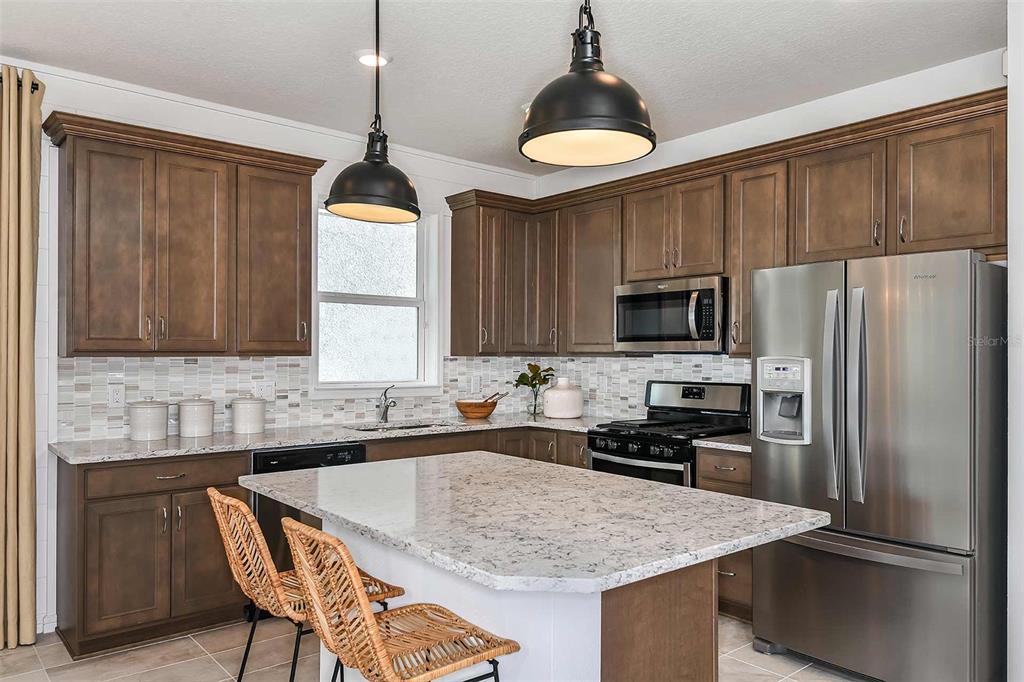 2354 Dew Drop Loop St. Cloud, FL 34771 - Photo 7 of 31 a kitchen with stainless steel appliances a stove center island and a refrigerator