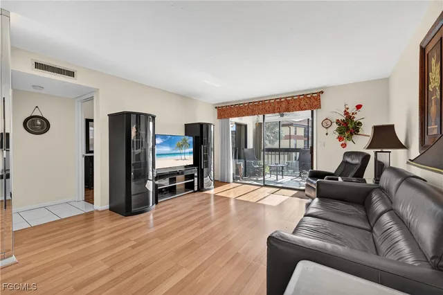 a living room with furniture flat screen tv and a refrigerator