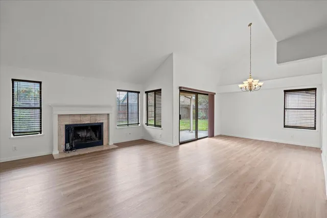 an empty room with wooden floor fireplace and windows