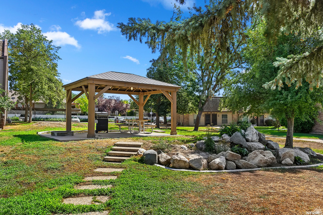 88 West 50 South, Unit J10 Centerville, UT 84014 - Photo 19 of 19 Central wooden gazebo with a metal roof, resting on a concrete pad with a built-in grill and picnic table