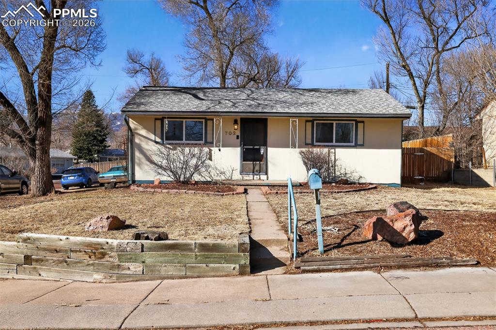 View of front of property featuring covered porch, a shingled roof, and stucco siding