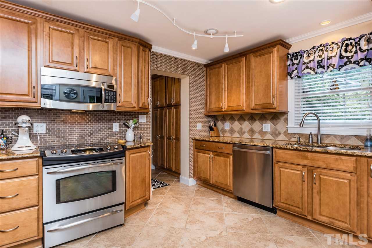 2808 Oberry Street Raleigh, NC 27607 - Photo 9 of 24 a kitchen with granite countertop wooden cabinets stainless steel appliances and a window
