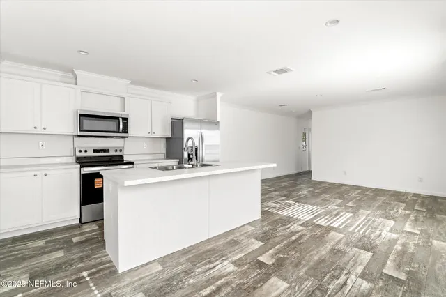 a view of a hallway with wooden floor and a bathroom
