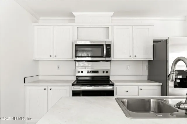 a kitchen with stainless steel appliances white cabinets a sink stove and refrigerator