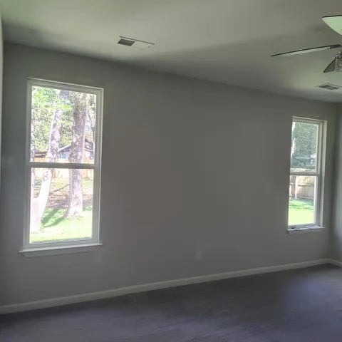 a view of an empty room and chandelier fan