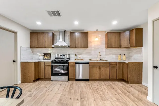 a large kitchen with stainless steel appliances granite countertop a stove a sink and a refrigerator