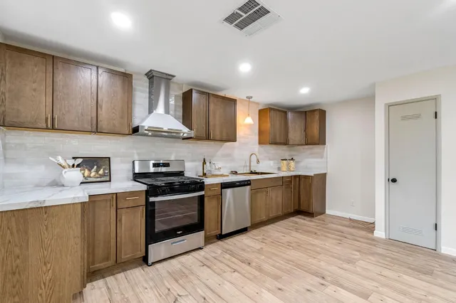 a kitchen with stainless steel appliances granite countertop wooden cabinets a sink a stove a refrigerator and microwave