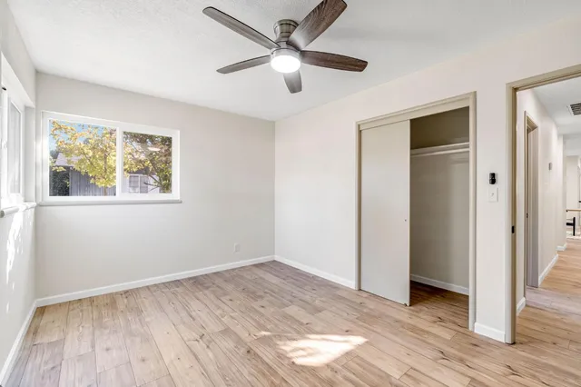 a view of empty room with wooden floor and fan