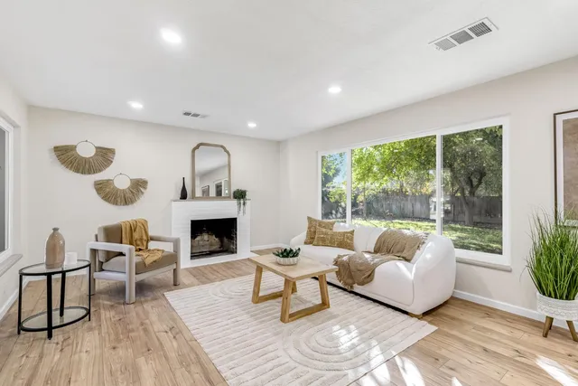 a living room with furniture a fireplace and a floor to ceiling window