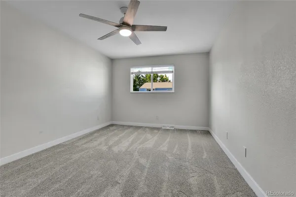 an empty room with windows and fan