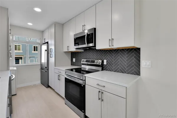 a kitchen with stainless steel appliances granite countertop a stove a sink and a microwave
